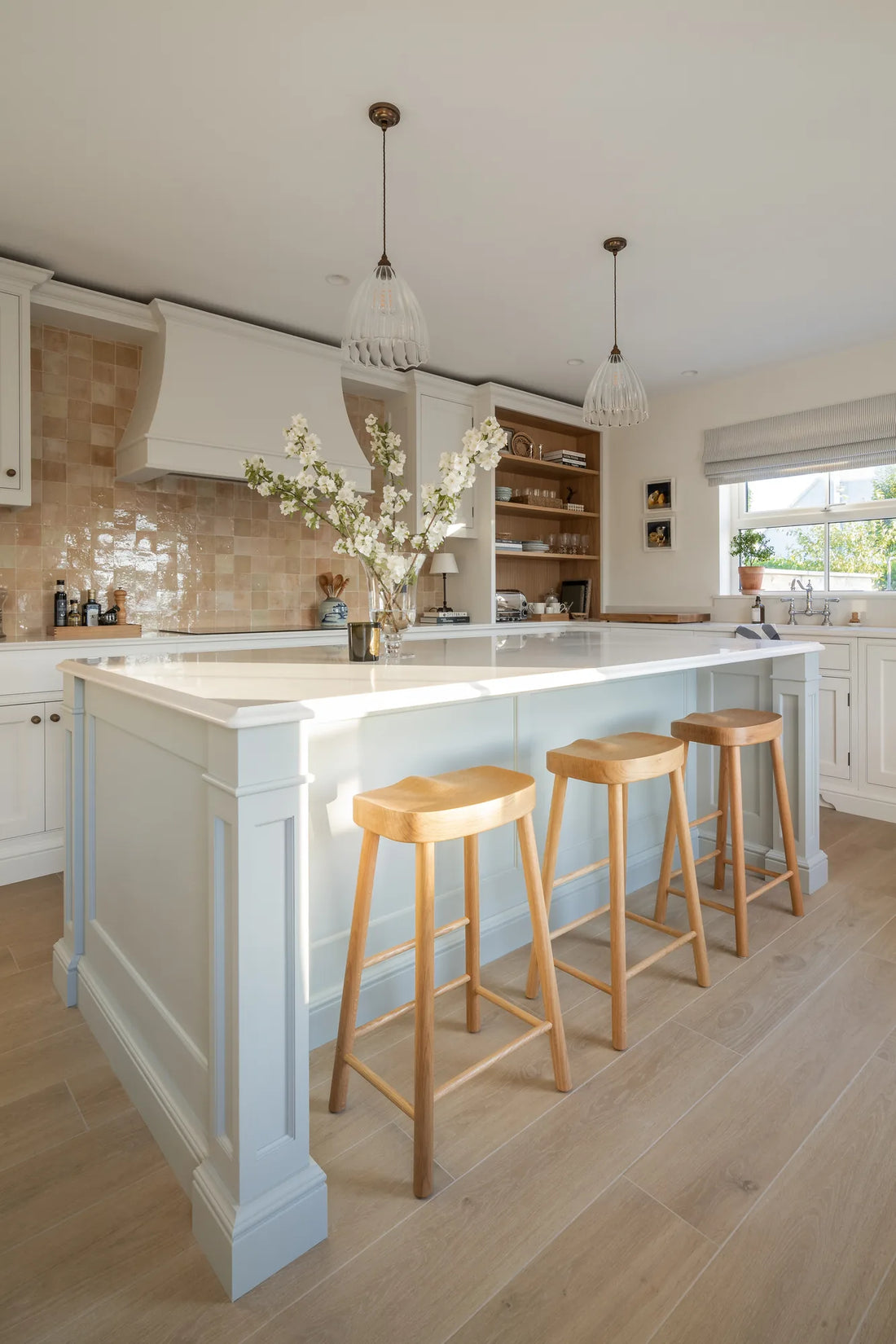 Bright country kitchen with a clay zellige tile backsplash, white island and oak bar stools