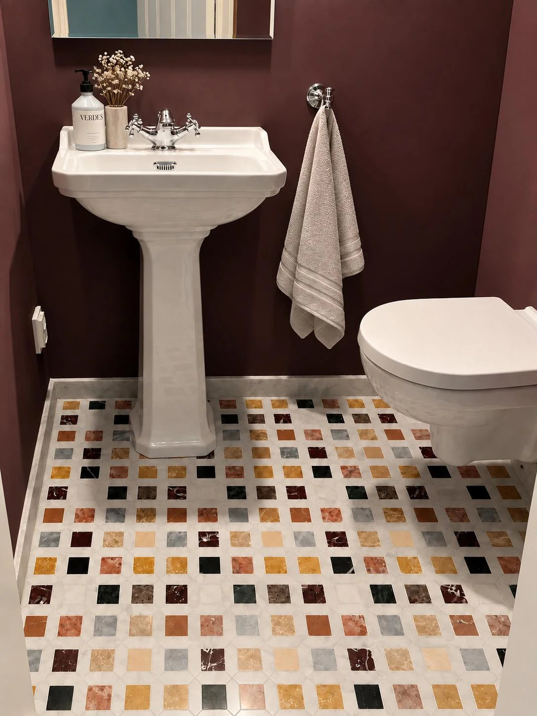 Mixed marble colourful mosaic floor in a burgundy cloakroom with white octagon tile borders