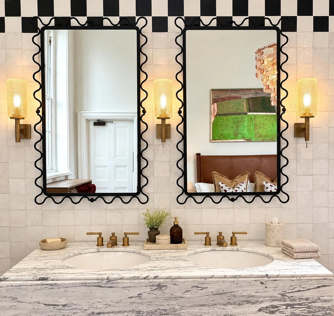 Pure white zellige tile wall above a marble double vanity with two black wavy mirrors