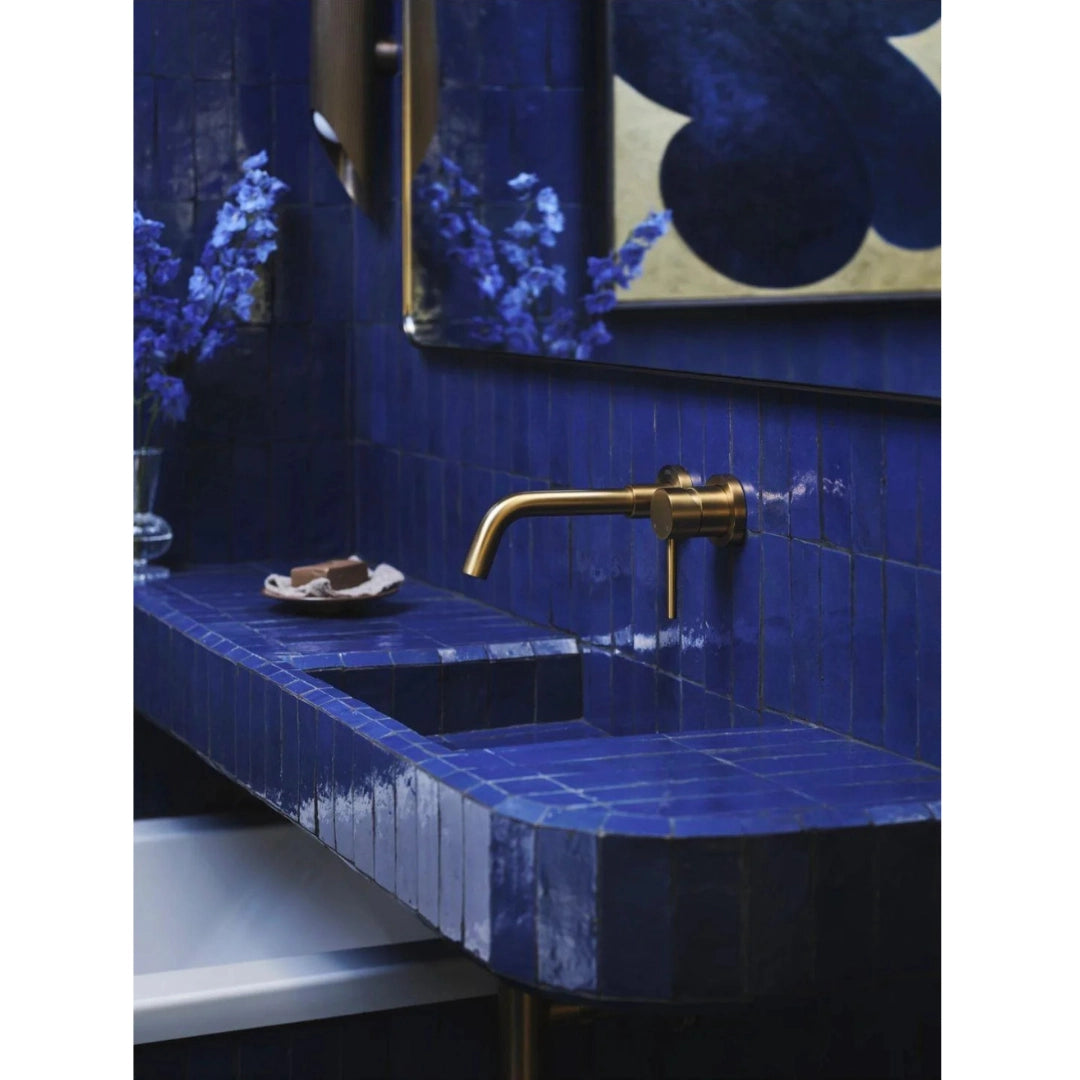 Royal blue bejmat tiles covering a bathroom basin and wall with a brass tap