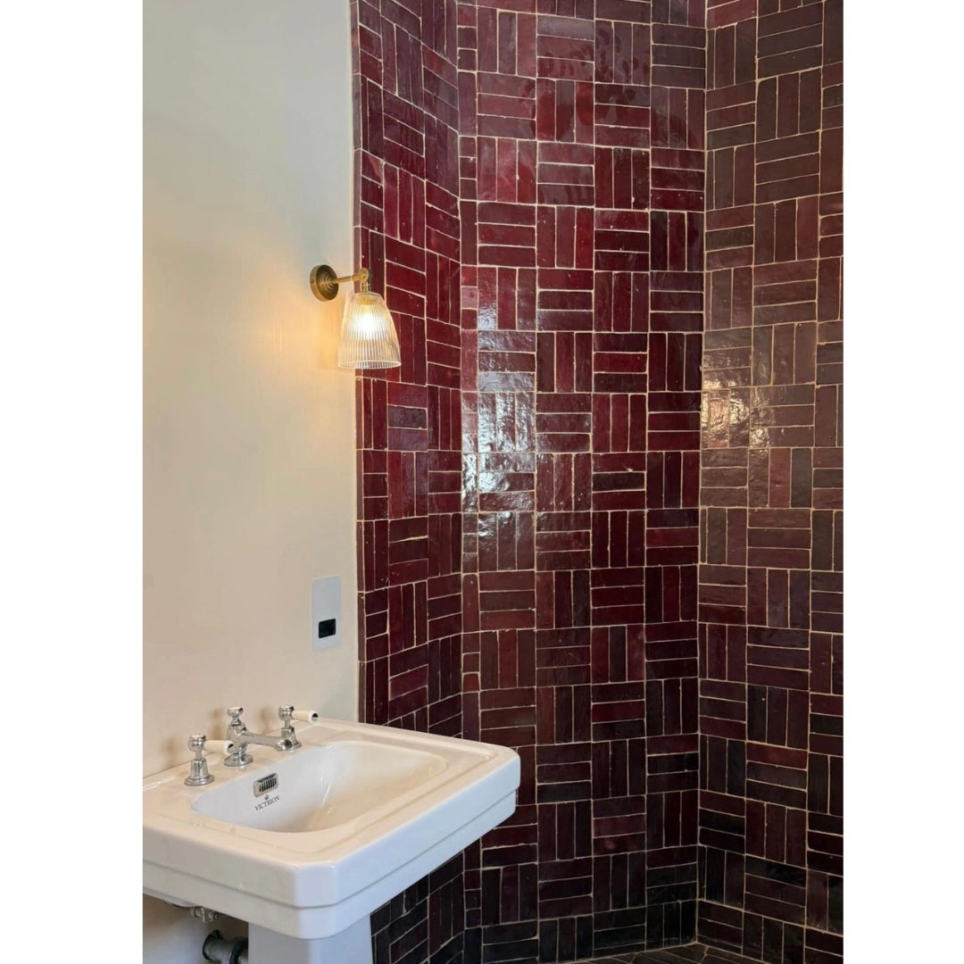 Ruby red bejmat tiles in a basketweave pattern on a bathroom wall above a pedestal sink